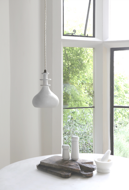 white pendant light in a kitchen with dining table and white interior